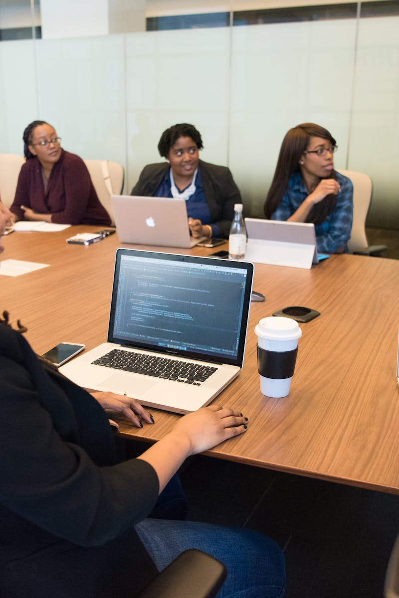 Adults reviewing information together around a meeting table with laptops.
